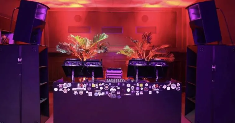 DJ studio with decks and speakers in warm red light, where Kirill took his first lesson