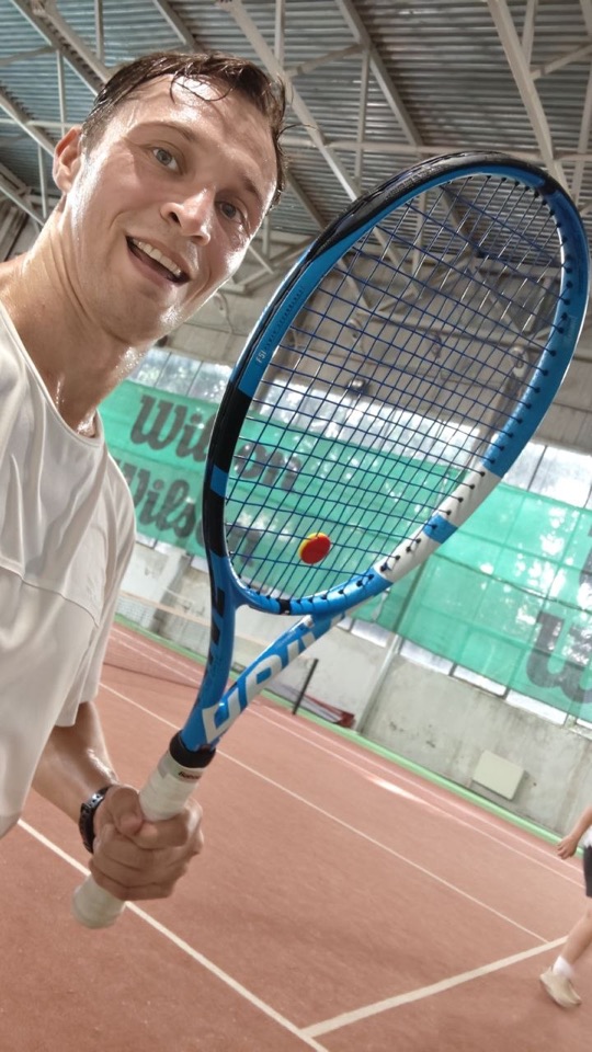 Kirill holding a tennis racket on an indoor court